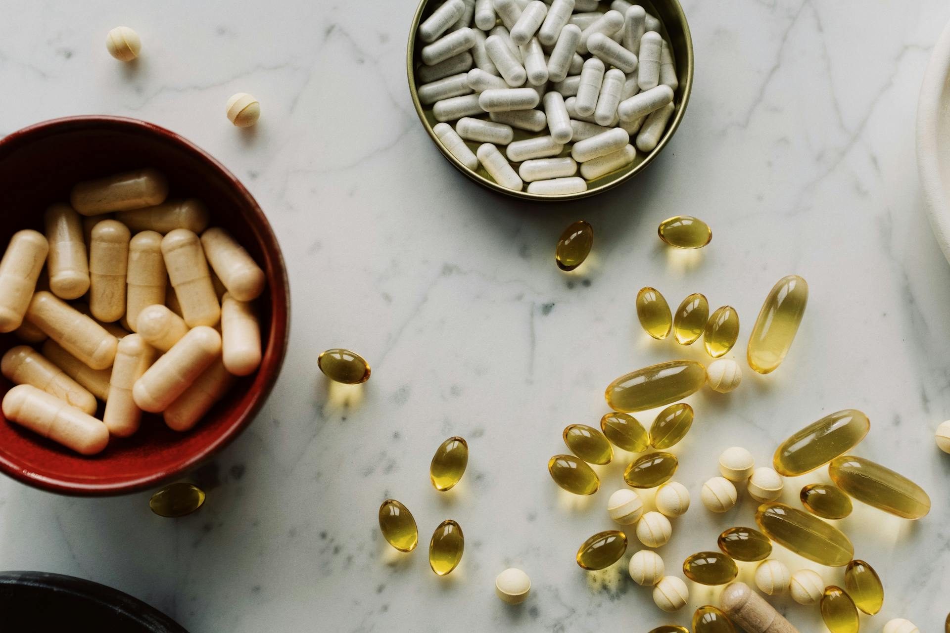 Top view of various supplements and capsules arranged on a marble surface with ample copy space.