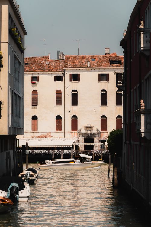 Free Scenic view of a Venetian canal with historic buildings and boats on a sunny day. Stock Photo