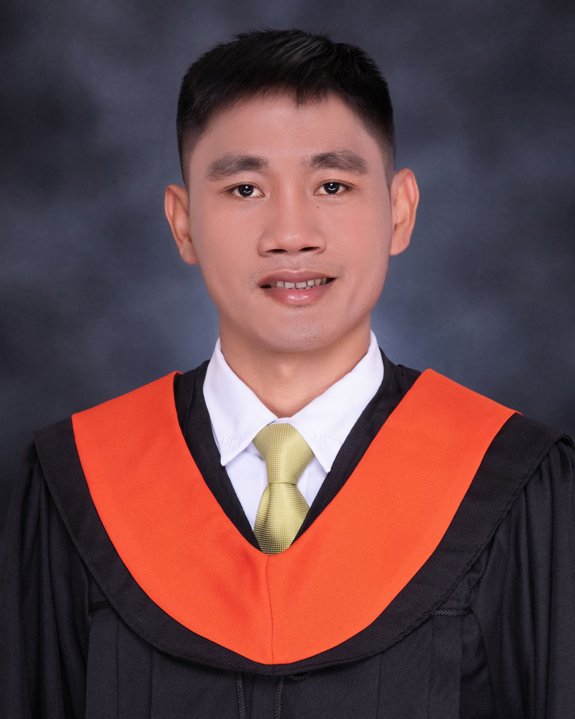 Professional studio portrait of a male graduate wearing a cap and gown with a neutral background.