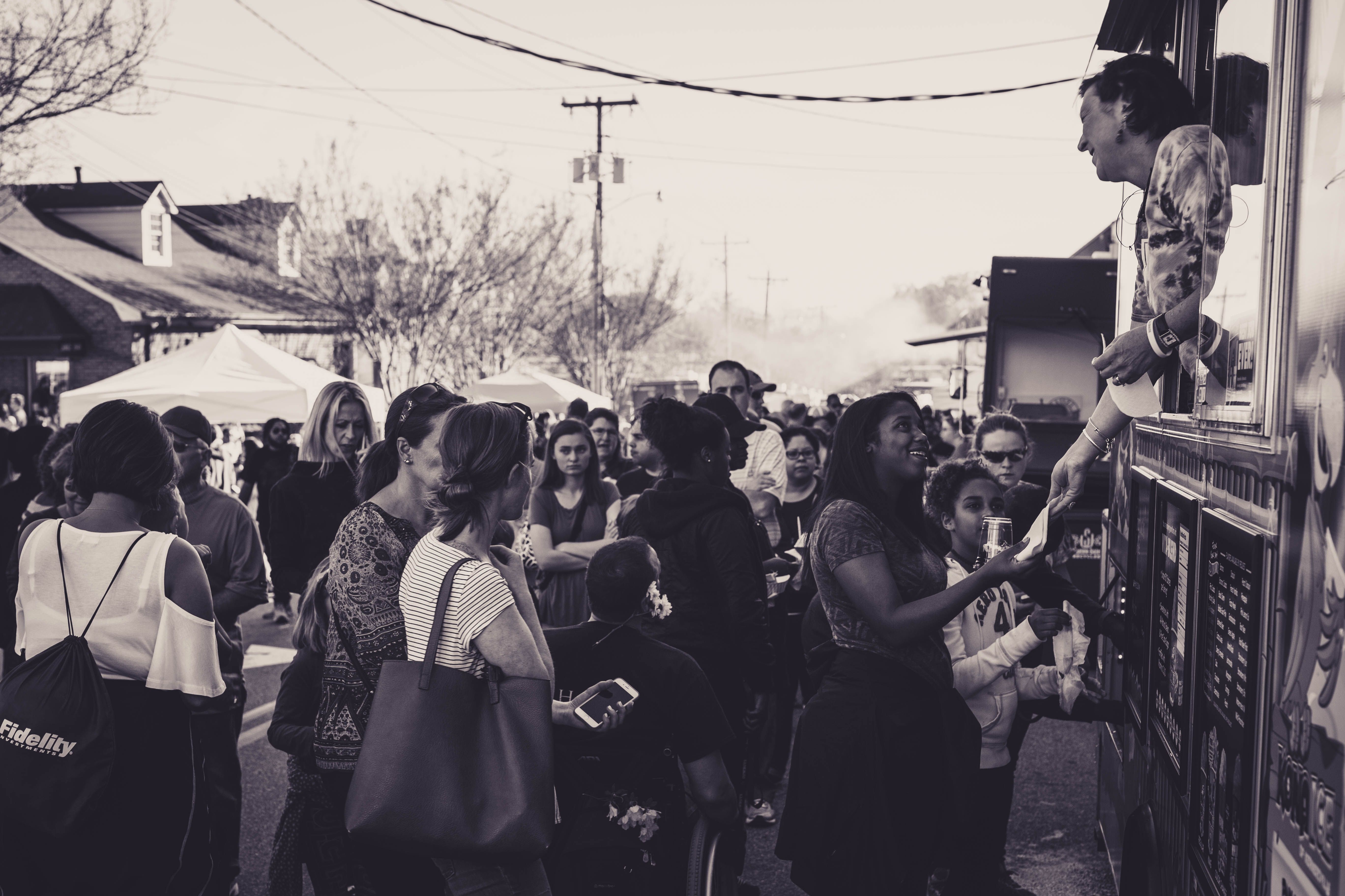 A local Armidale small business owner interacting with diverse community members during a market day event.