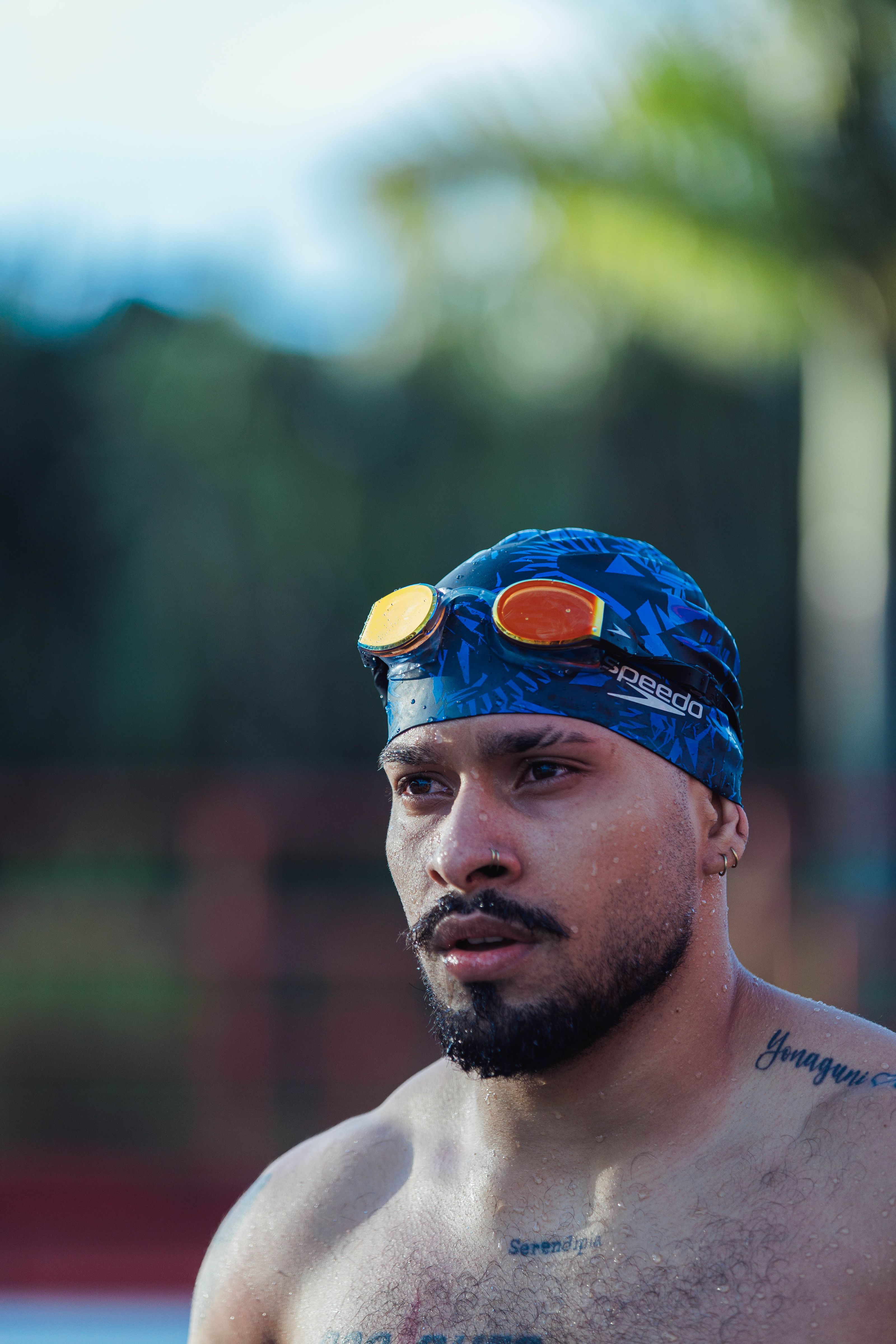 Close-up de um nadador masculino e focado usando óculos e touca ao ar livre, pronto para competir.
