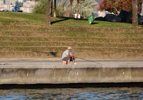 Free A man fishing along the waterfront in İzmir, Türkiye during a sunny summer day. Stock Photo