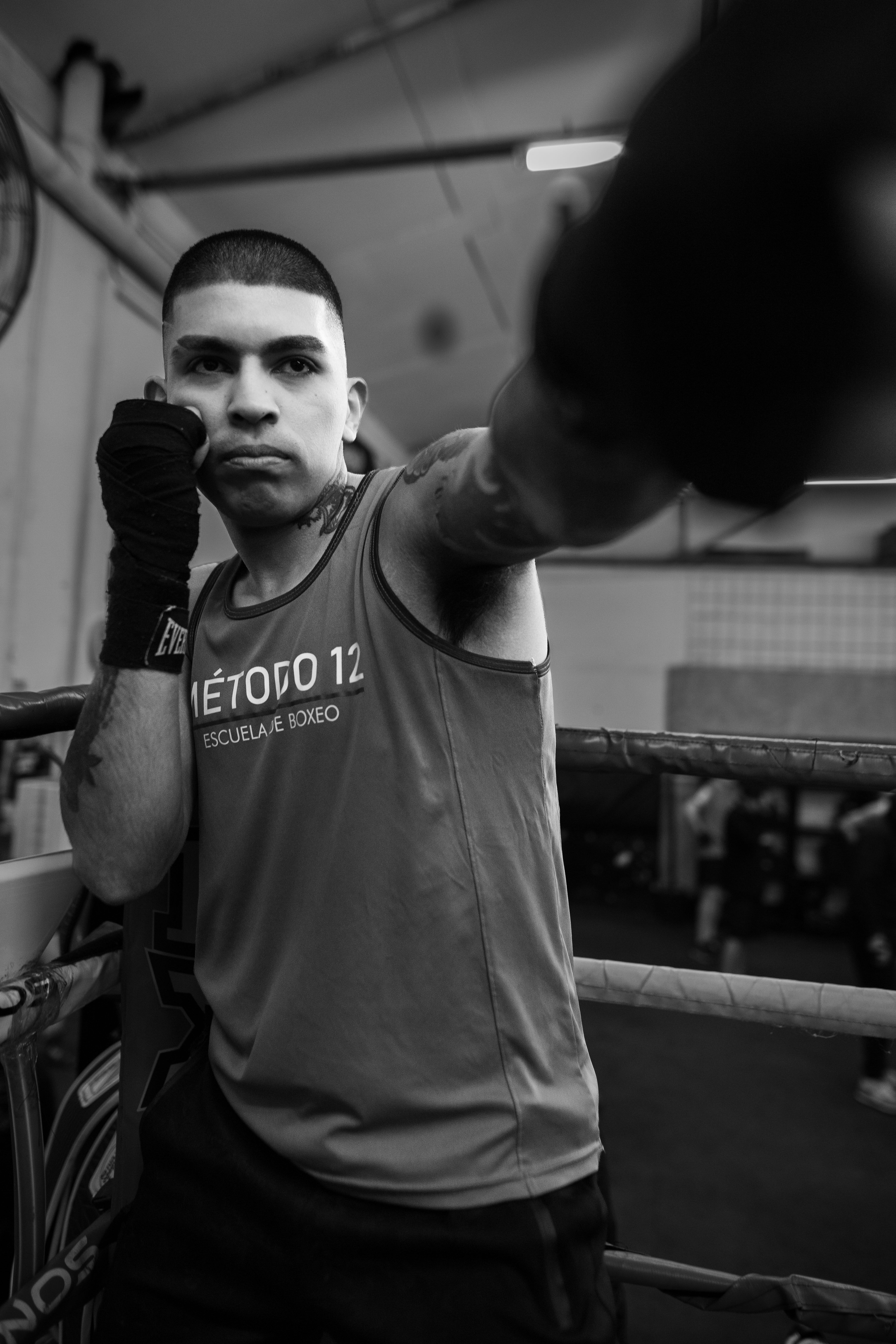 Black and white image of a boxer practicing at a gym in Buenos Aires, showcasing intense focus.