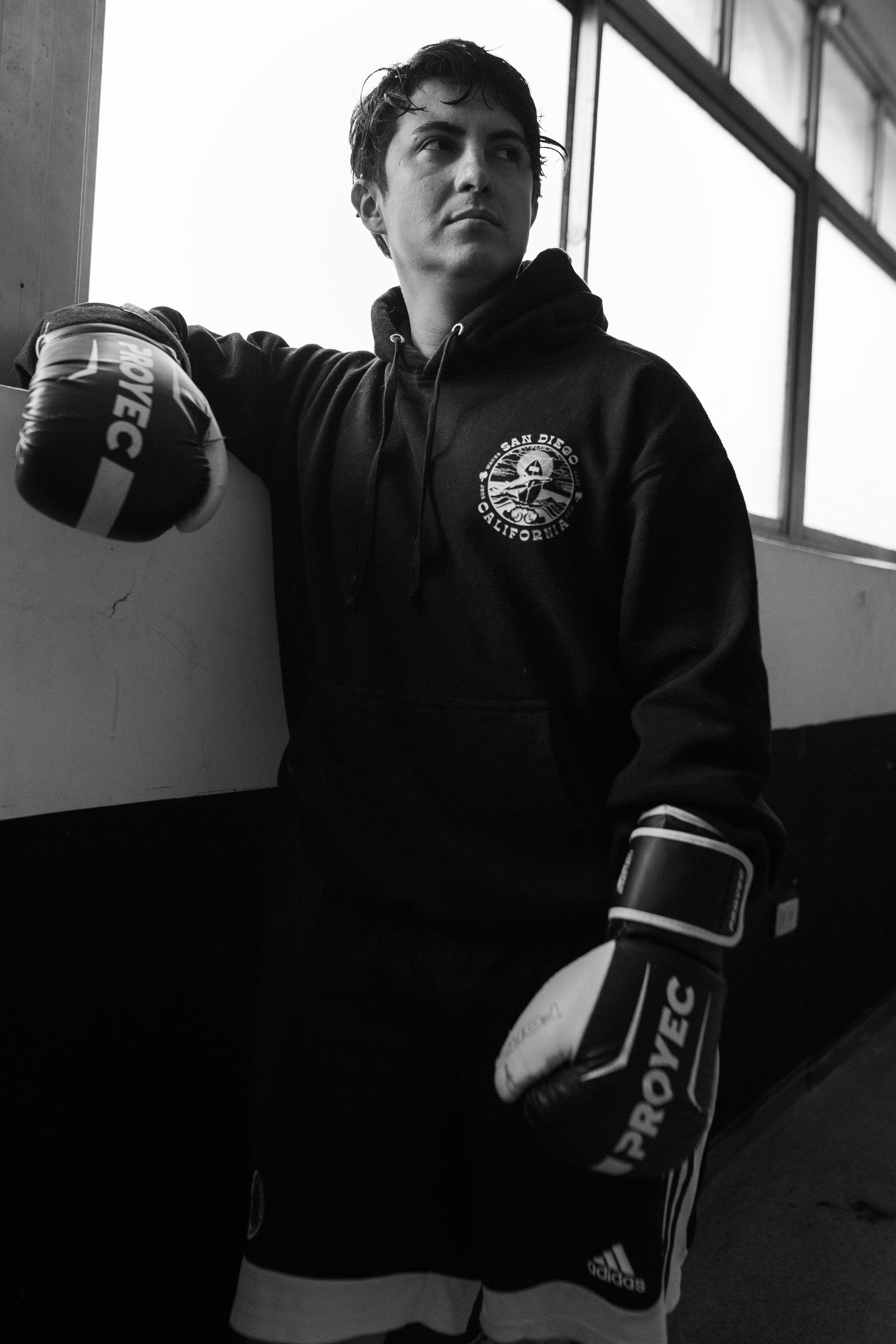Monochrome photo of a boxer wearing gloves, leaning on a wall in Buenos Aires.