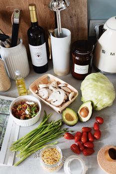 Top view of assorted healthy food and vegetables placed on tabletop near wine and utensils during home preparation for lunch