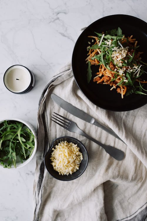 Salad with vegetables and herbs served on linen cloth with a candle on marble table