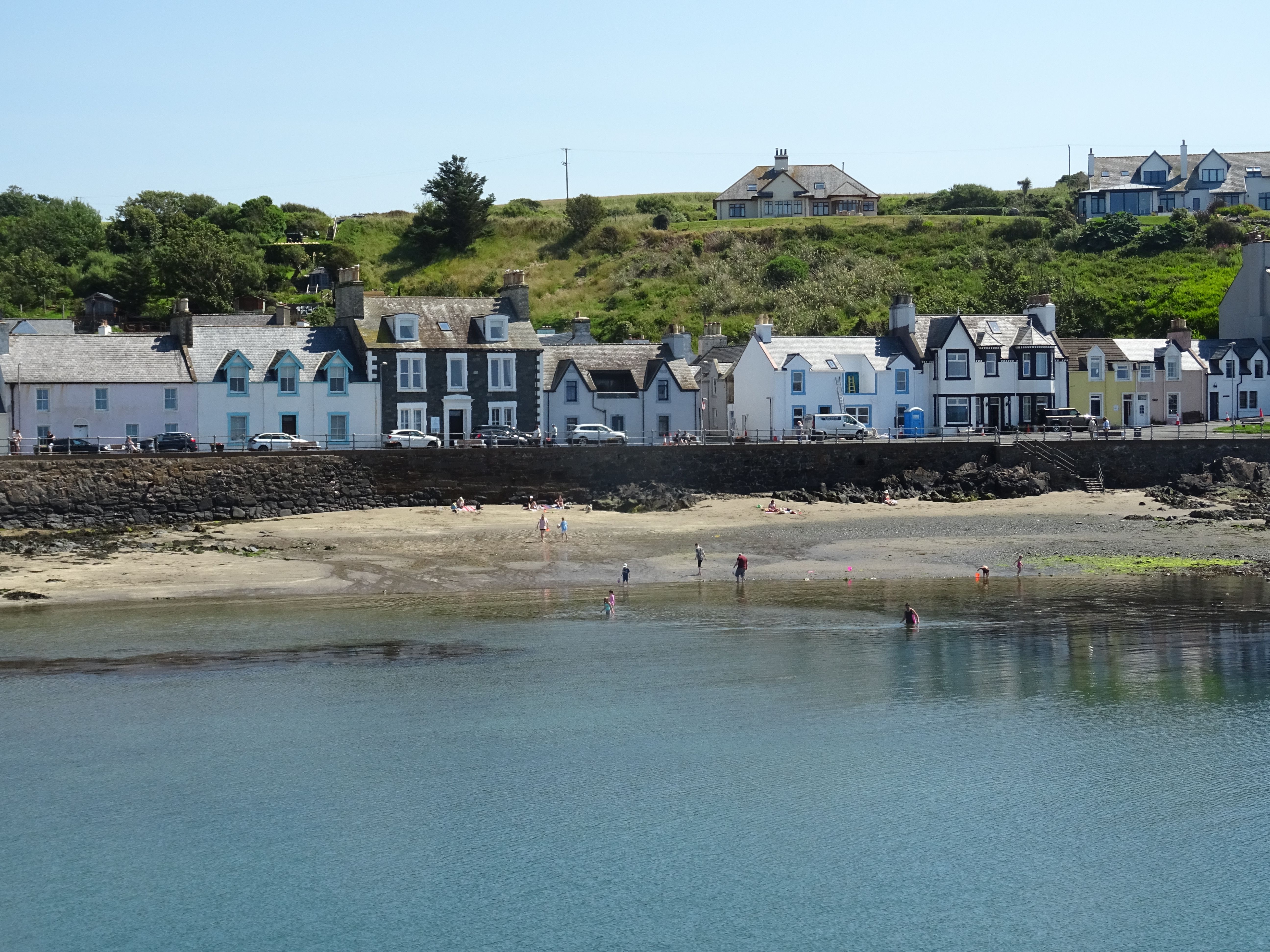 Picturesque view of Portpatrick's beachfront with charming houses lining the coast in summer.
