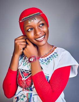 Portrait of a woman wearing vibrant traditional African clothing and jewelry, smiling joyfully.