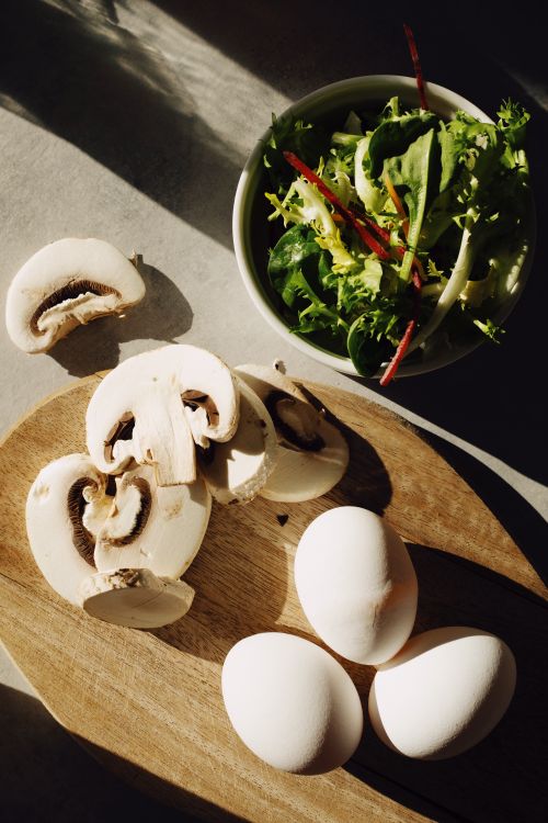 Free Close-up of fresh salad ingredients: mushrooms, eggs, and greens on a wooden board. Stock Photo