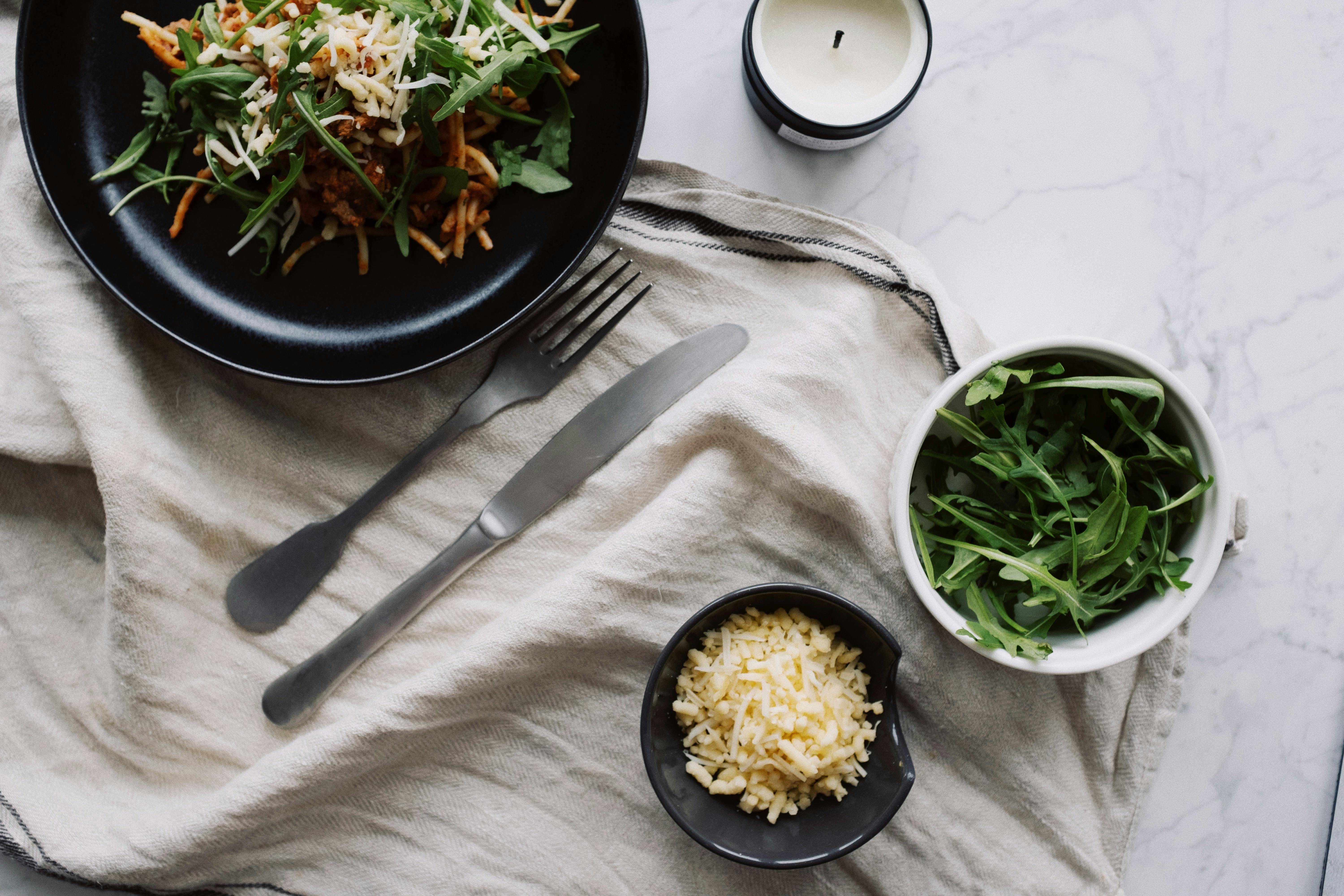 Fresh salad served on black plate with fork and knife on white napkin ...