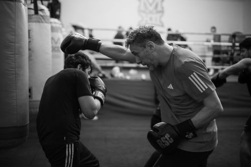 Free Black and white close-up of two men engaged in a dynamic boxing training session indoors. Stock Photo