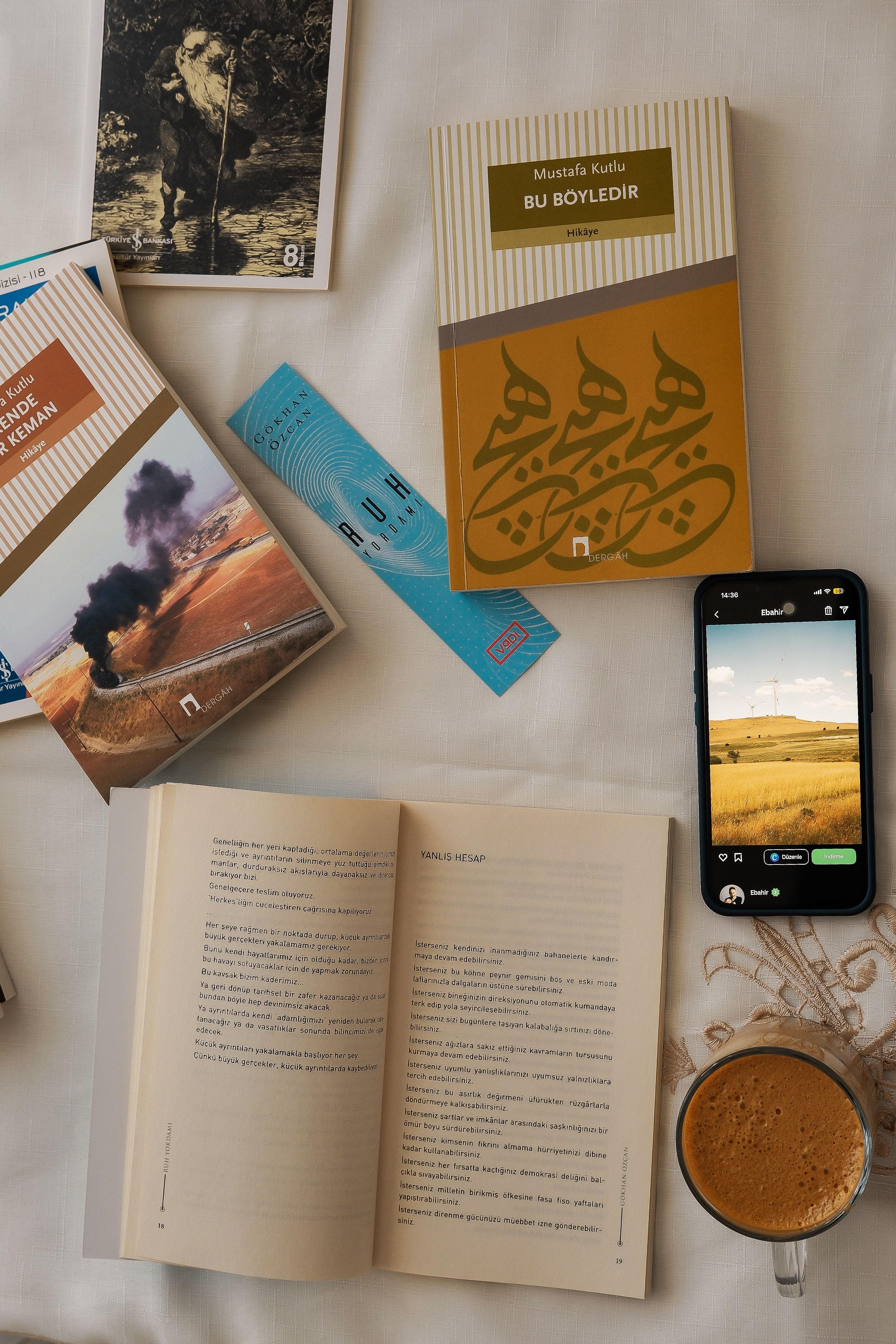 Overhead view of books, coffee, and a smartphone on a neutral surface, perfect for a cozy reading vibe.