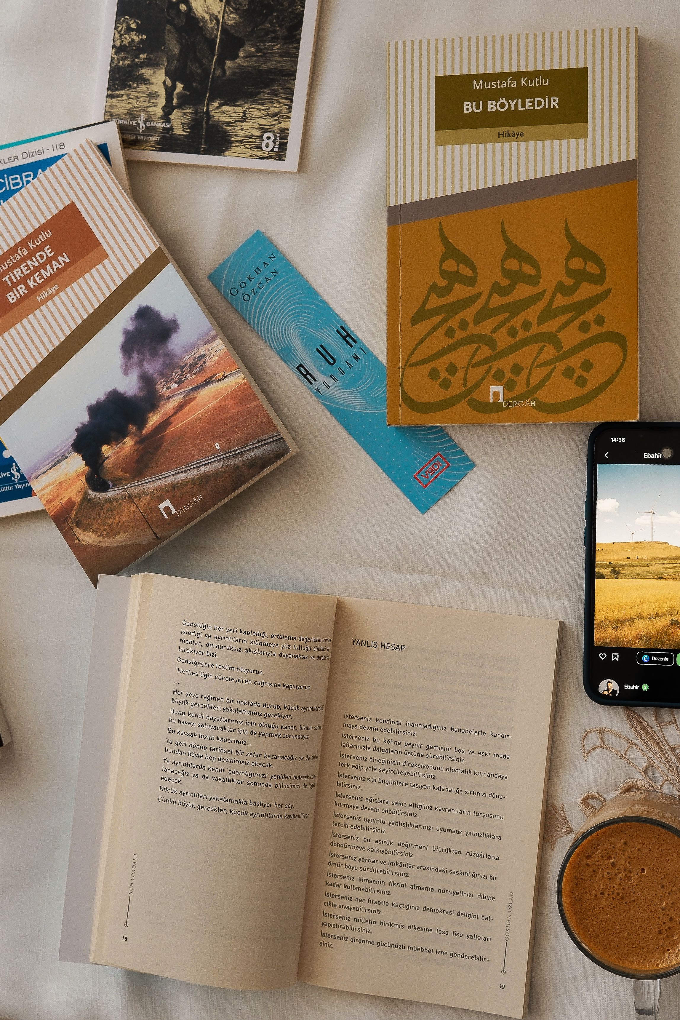 Warm flat lay featuring books, coffee, and a smartphone on a white surface, adding a cozy vibe.