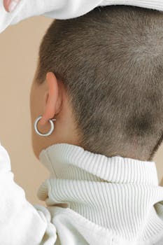 一名女子穿着高领毛衣的背影，露出平头和圆环耳环