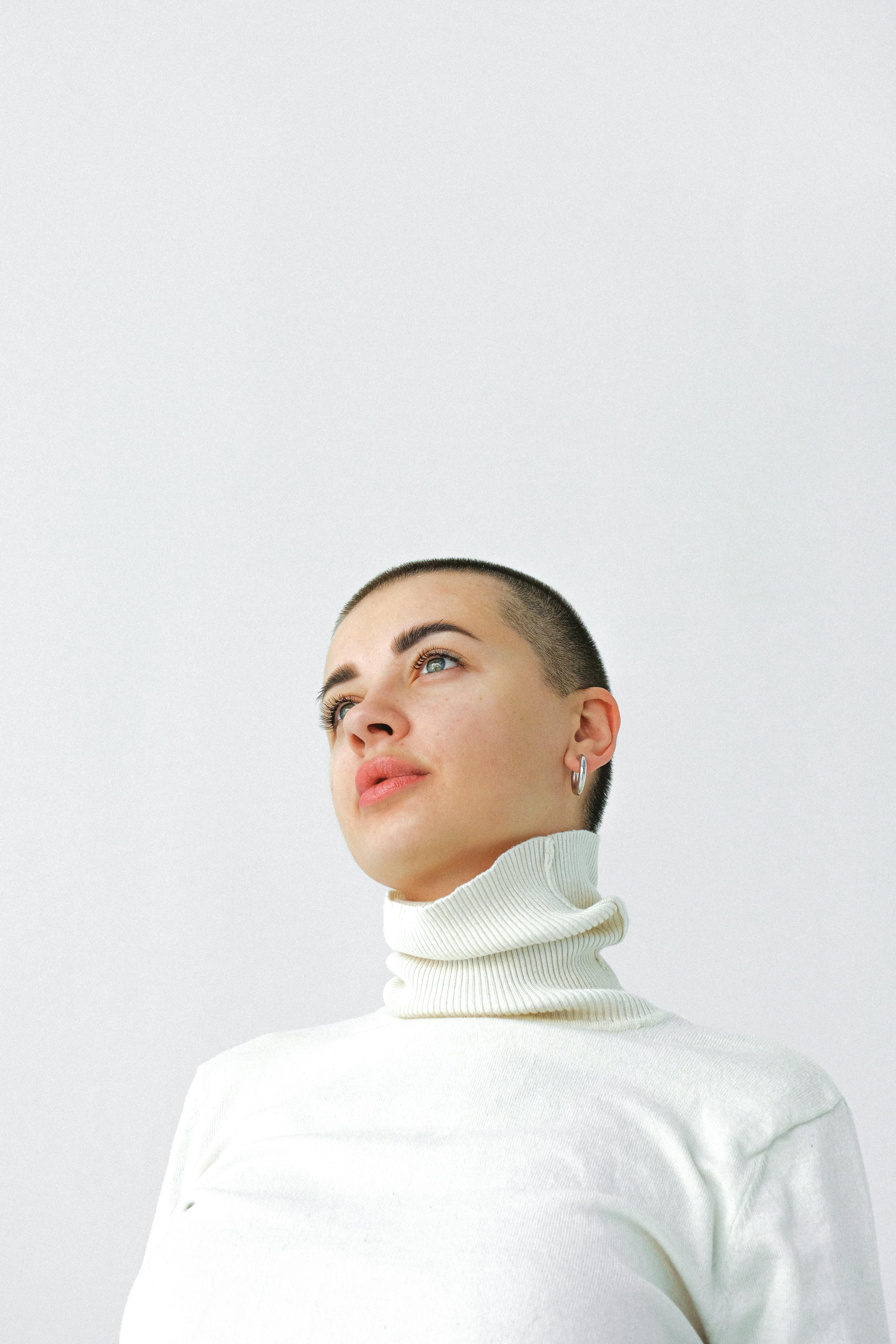 Minimalist portrait of a young woman in a turtleneck against a white background.