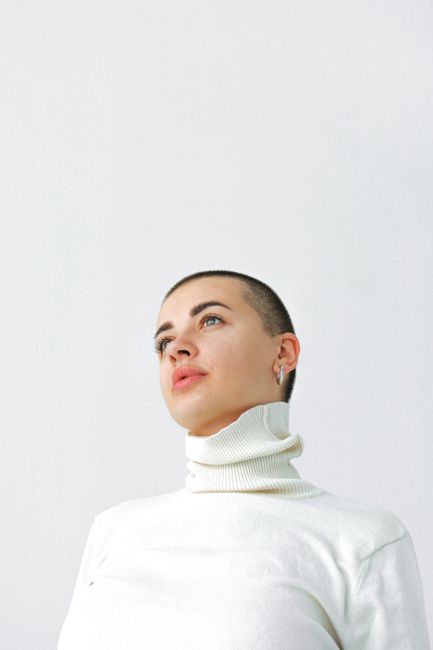 Minimalist portrait of a young woman in a turtleneck against a white background.