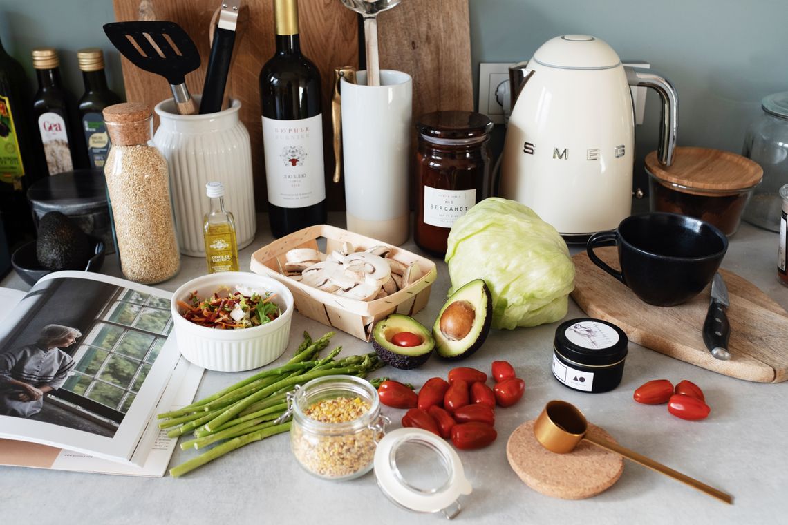 Kitchen countertop with fresh ingredients, cookware, and an electric kettle