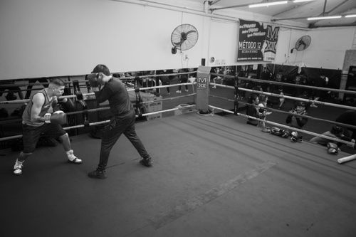 Free Boxing training session in an indoor gym in Argentina. Coach guiding young boxer on technique. Stock Photo