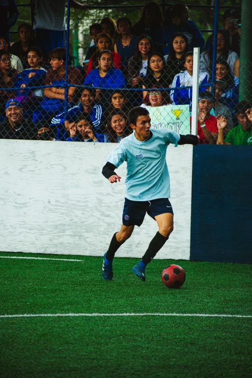 Free Amateur football player in action during a match in Ciudad de México, with a cheering crowd in the background. Stock Photo