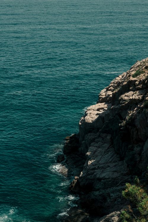 Free Rugged rocky coastline meeting the Mediterranean Sea in Tossa de Mar, Spain. Stock Photo