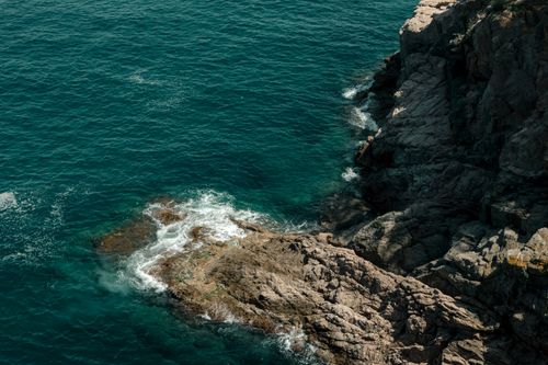Free Aerial view of the rocky coastline at Tossa de Mar with turquoise sea waves. Stock Photo