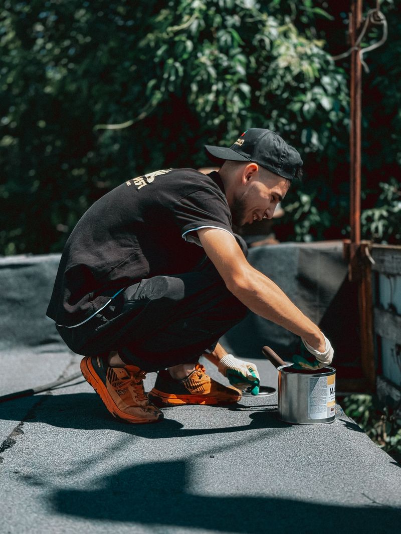 Worker applying sealant coating to a rooftop in sunshine