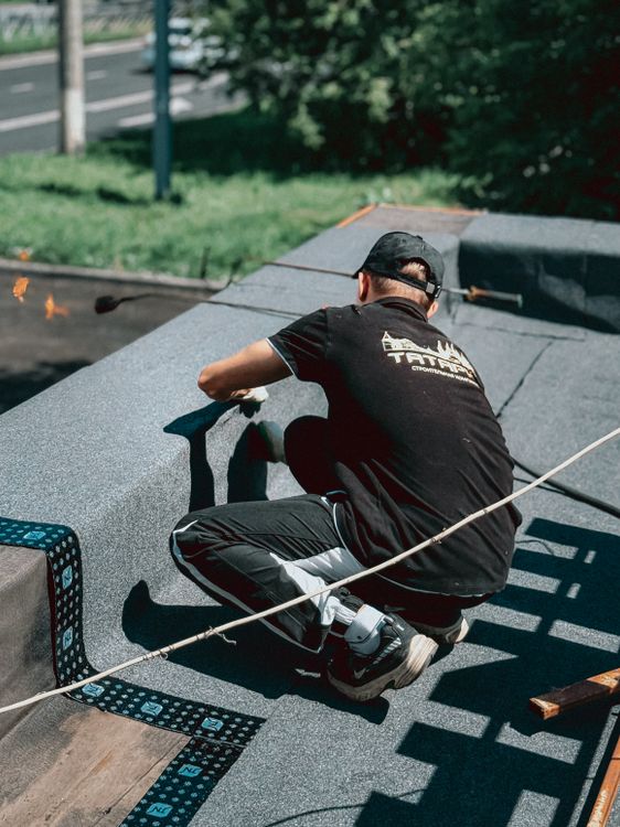 Roofer installing roofing material on a flat roof in bright daylight