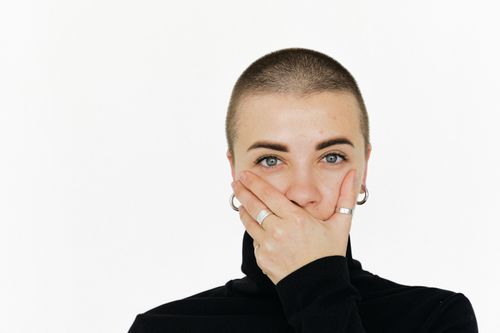 Free Close-up portrait of a woman with a surprised expression, covering her mouth, on a plain white background. Stock Photo