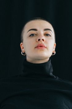 这是一位身穿黑色高领毛衣、戴着圆环耳环的自信年轻女子的特写肖像