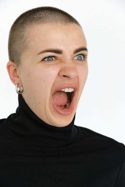 Close-up portrait of a woman with intense facial expression and open mouth.