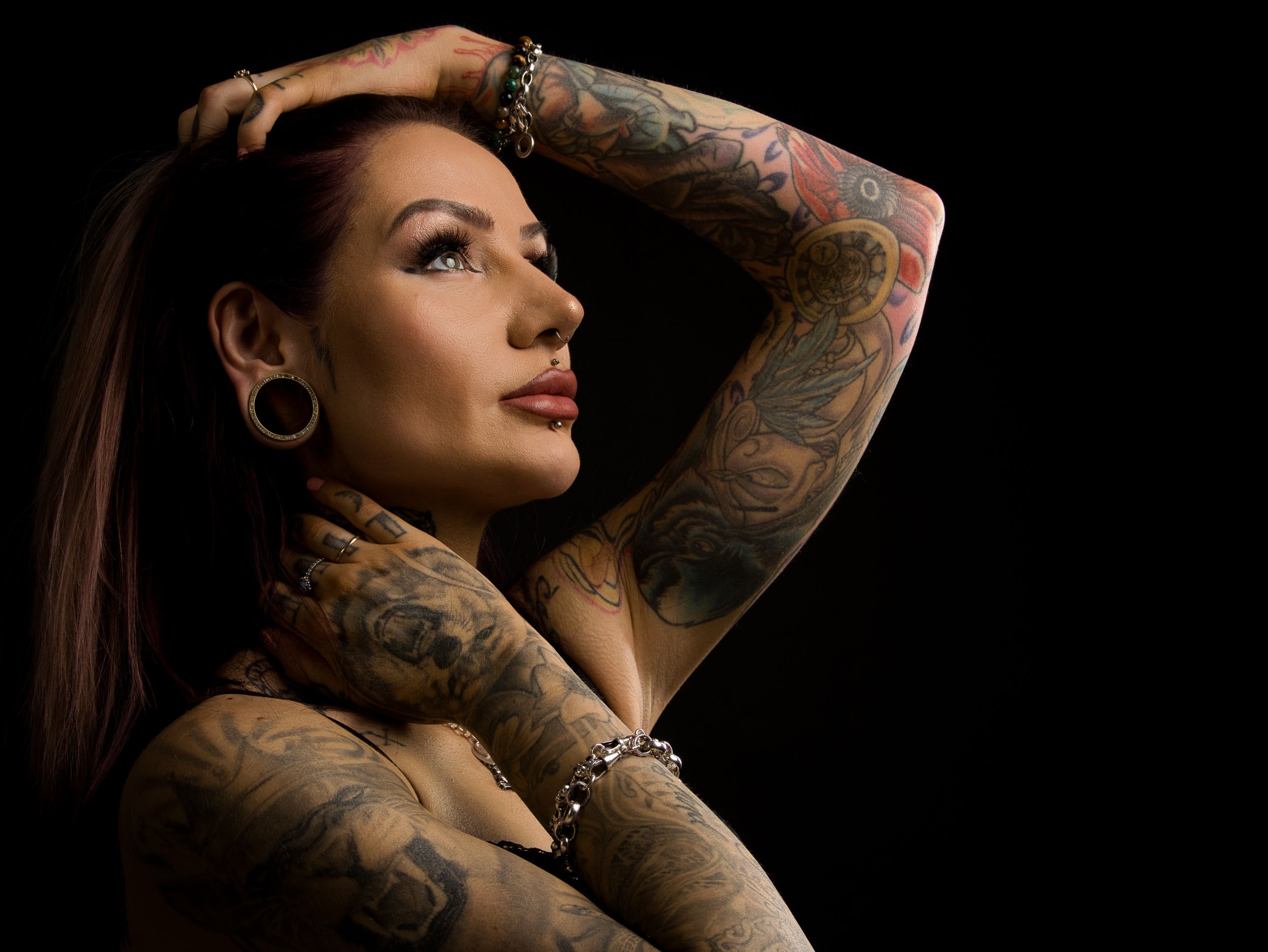 Close-up portrait of a tattooed individual with dramatic lighting against a dark background.