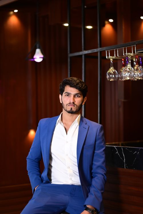 Free Portrait of a confident man in a blue suit posing indoors with sophisticated lighting. Stock Photo