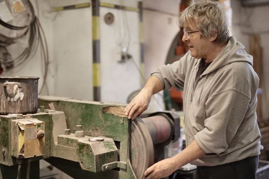 Senior man working with metal details in workshop