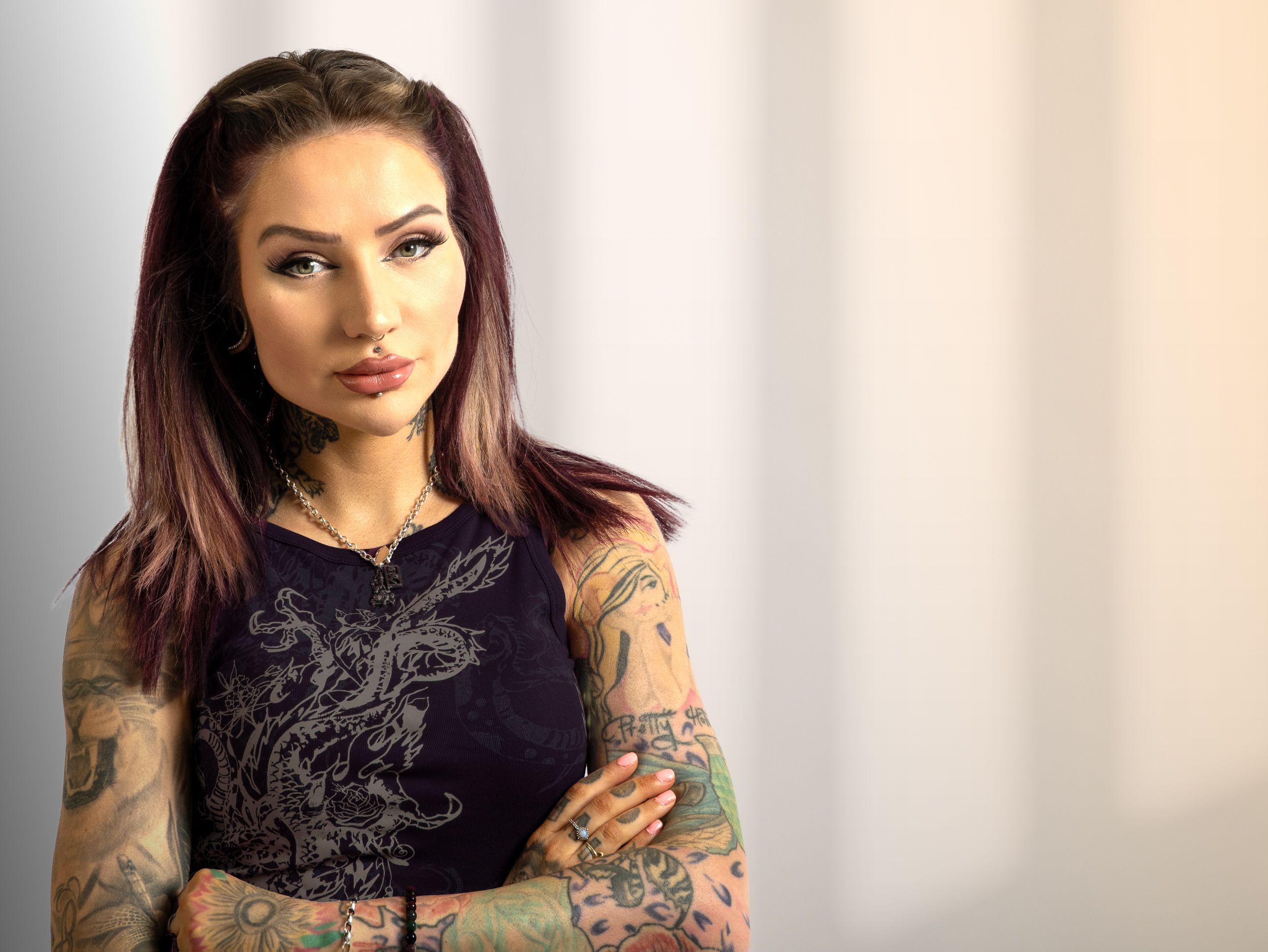 Portrait of a confident woman with tattoos and piercings in a studio setting.