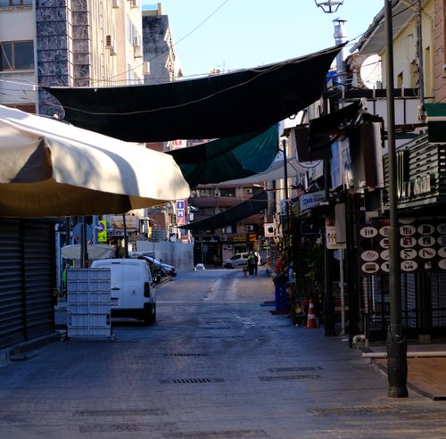 Free Sunlit alley in İzmir, Turkey with closed shops and vehicles lining the street. Stock Photo