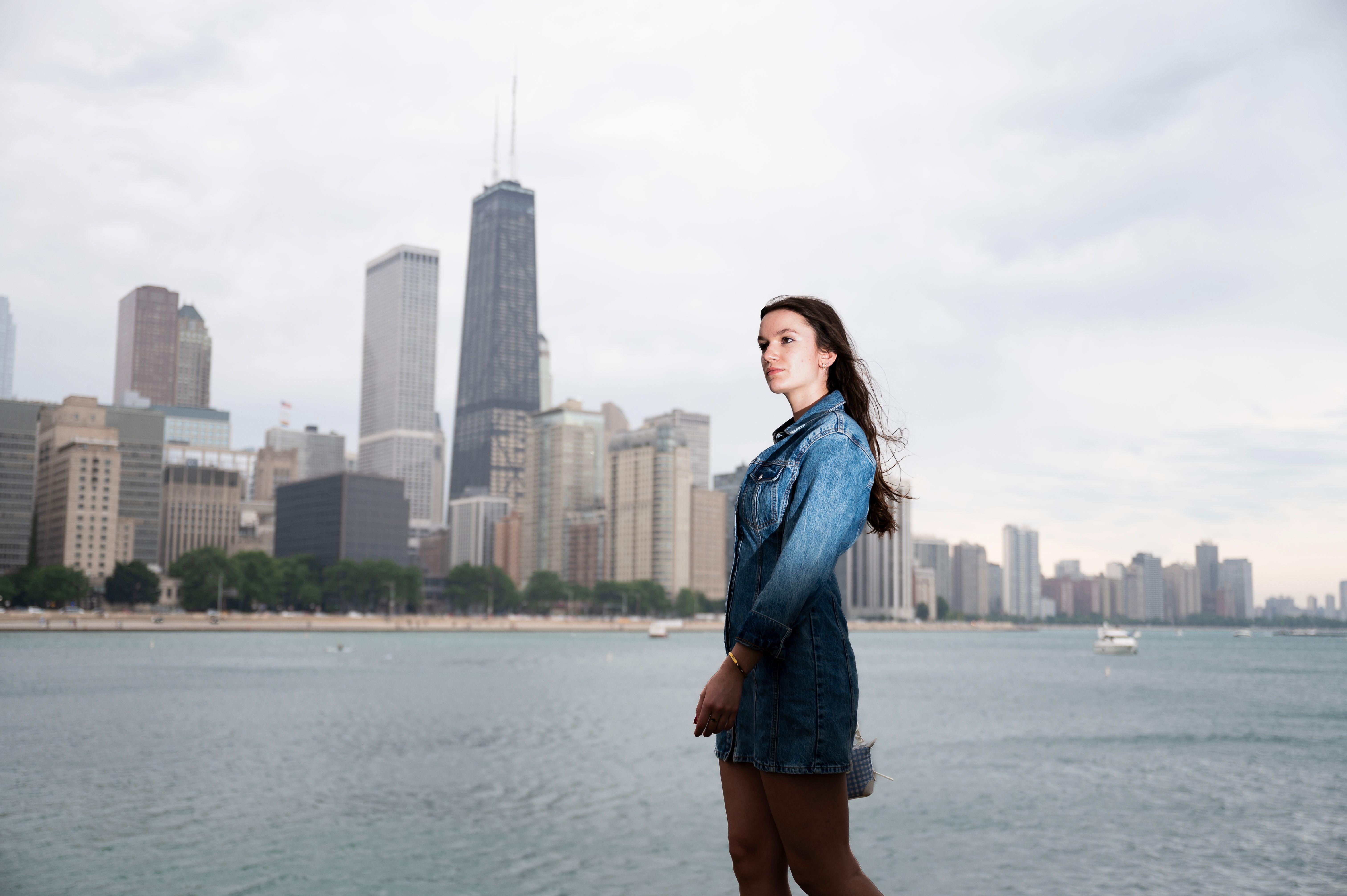 Woman in a denim jacket on the Lake Michigan waterfront with the Chicago skyline behind her