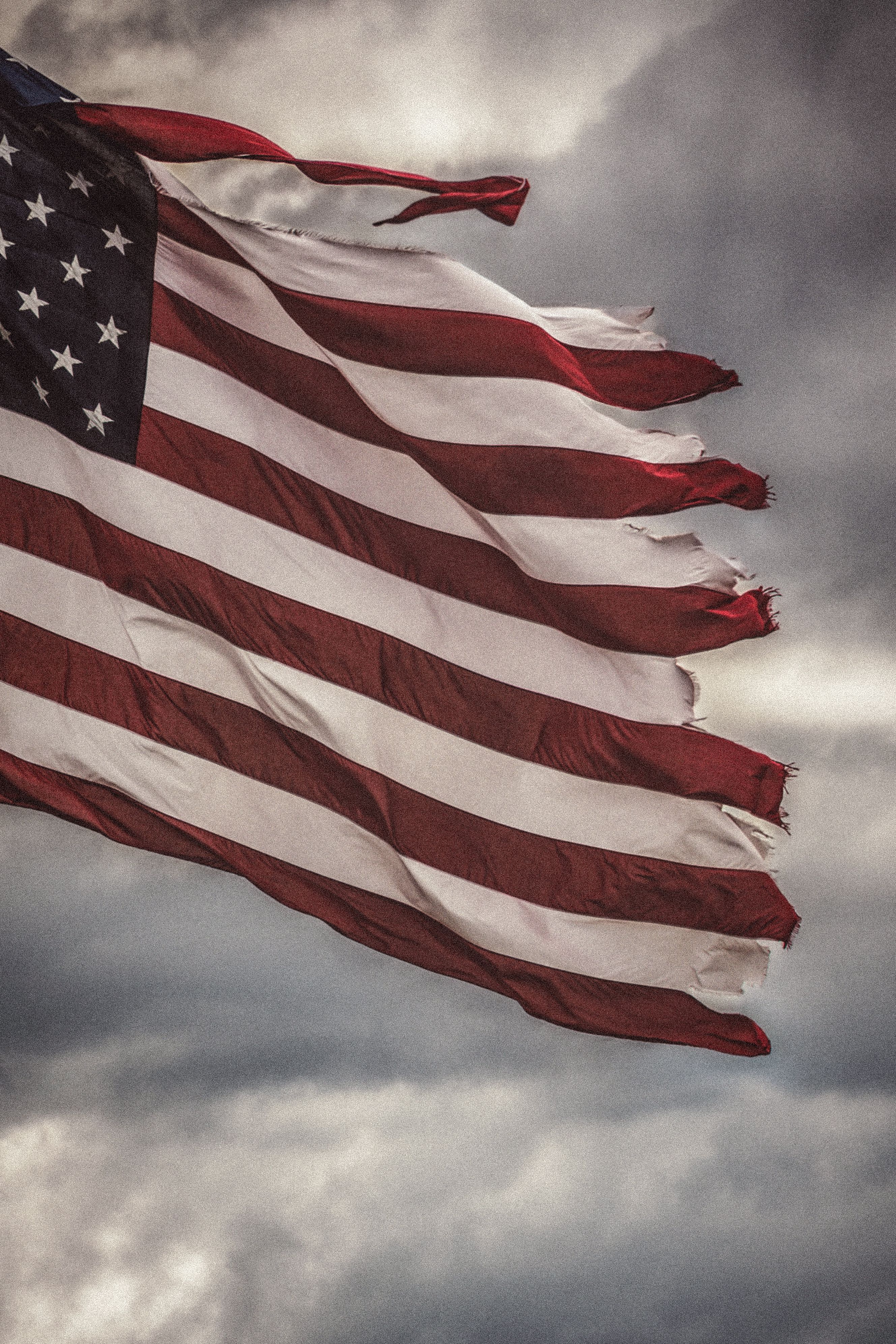 Weathered American Flag Against Stormy Sky · Free Stock Photo