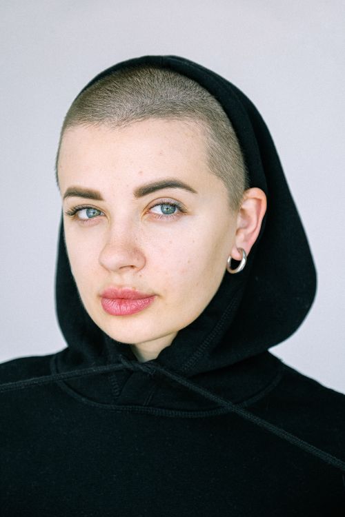 Free A close-up portrait of a woman in a black hoodie with short hair, showcasing minimalistic style. Stock Photo