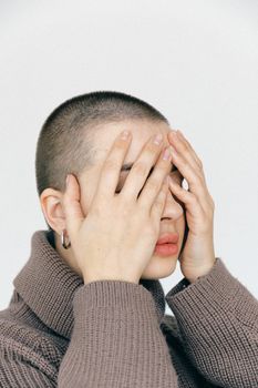 一名女子穿着针织衫，平静地遮住脸的特写