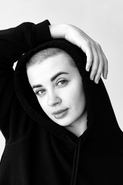 Free Striking black and white portrait of a woman posing in a hoodie, highlighting her expressive gaze. Stock Photo