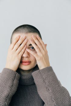 这是一幅女子的特写肖像，她身穿针织毛衣，用手捂住脸，神情沉思