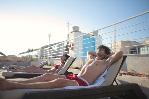 Couple sunbathing on sun loungers by pool