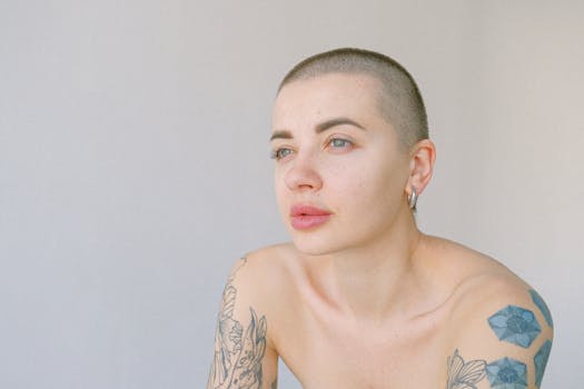 工作室特写肖像中，一位留着平头、蓝眼睛的纹身女子正看向别处