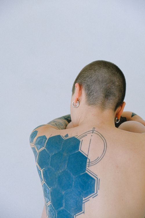 Free Minimalist portrait of a tattooed person with shaved head from behind, showcasing geometric art. Stock Photo