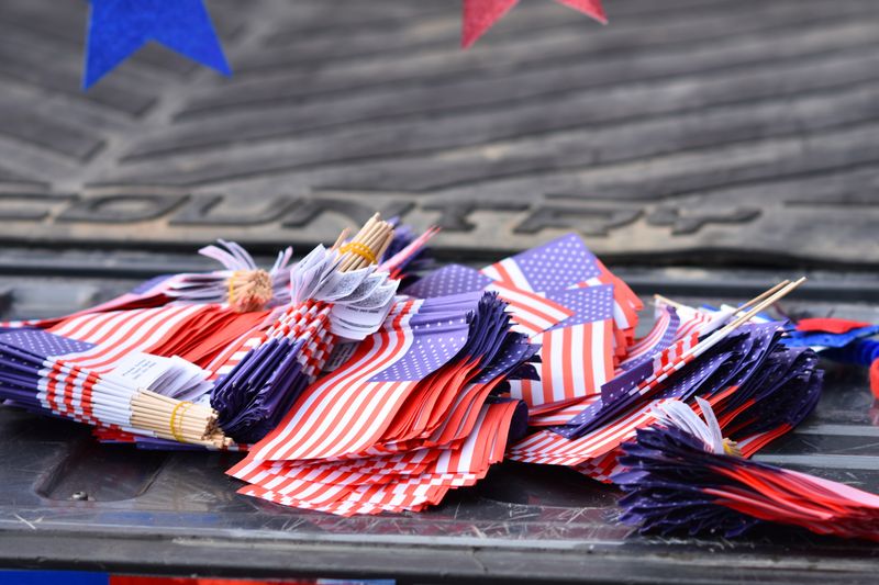 Flags mounted on the open tailgate of a pickup truck at an outdoor gathering