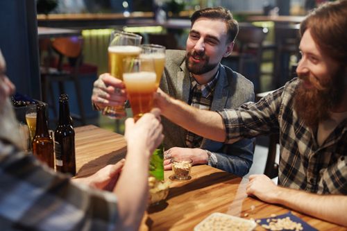 Free Group of friends toasting with beer glasses while celebrating at a pub. Stock Photo