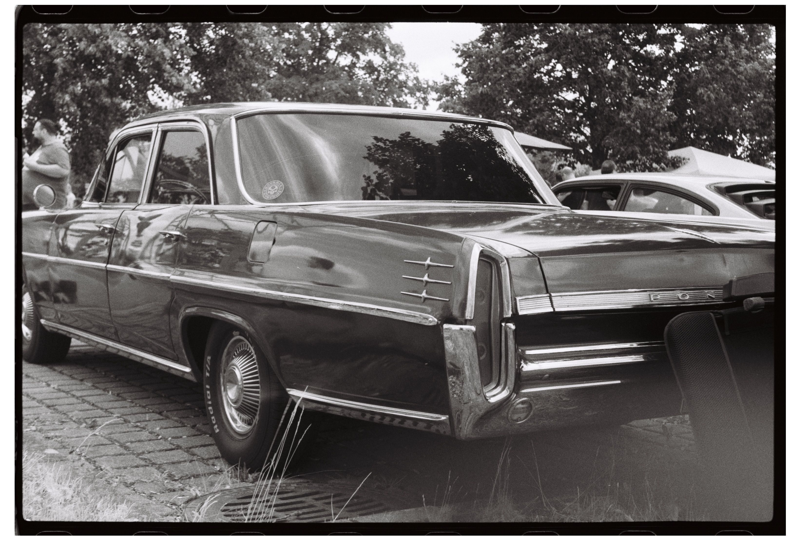 Black and white photo of a classic vintage car at an outdoor auto show.