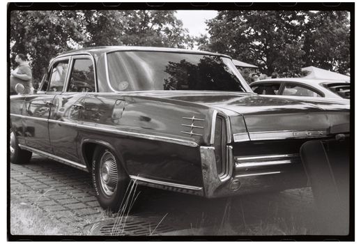 Black and white photo of a classic vintage car at an outdoor auto show.