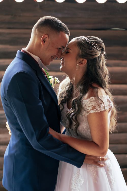 Free Happy couple in wedding attire embracing lovingly during their ceremony indoors. Stock Photo