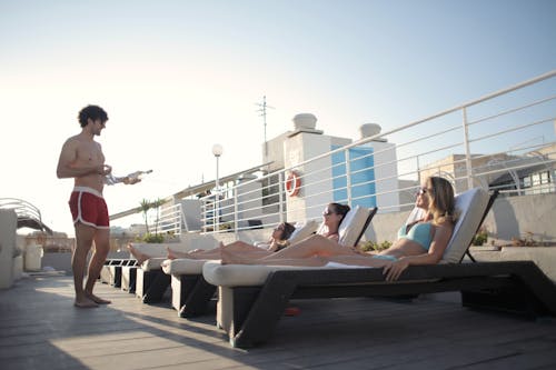 Young friends chilling on poolside together in summer